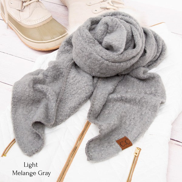 Light melange gray scarf on a white surface with shoes in the background