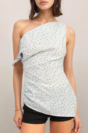 Woman wearing the baby blue one-shoulder polka dot top and black shorts against a plain background