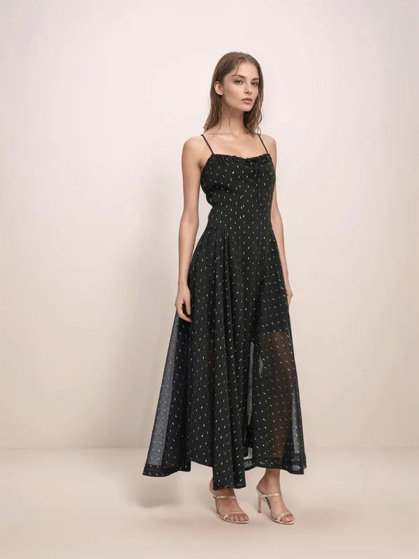 Woman wearing a black dress with silver polka dots on a beige background