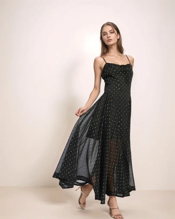 Woman wearing a black polka dot dress on a plain background