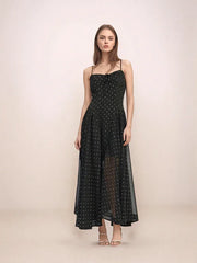 Woman wearing a black dress with white polka dots on a beige background