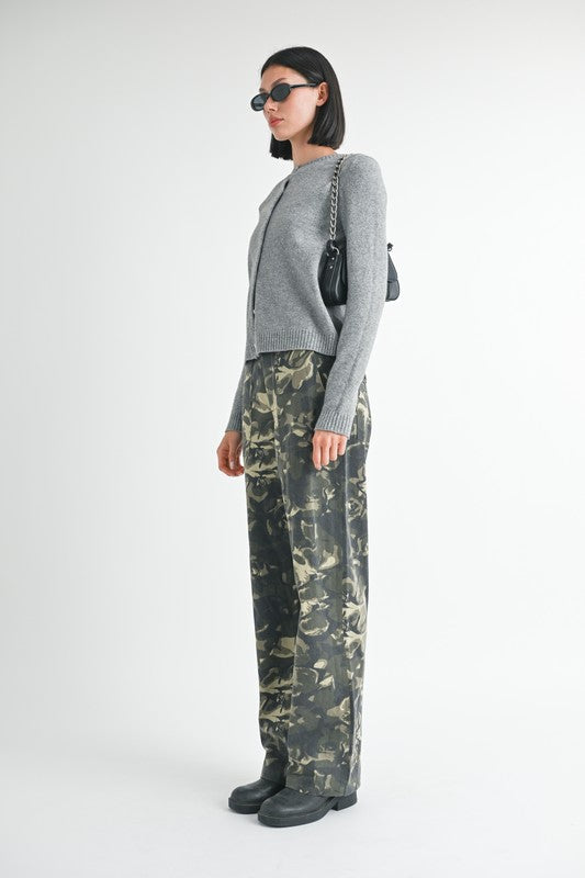 Person wearing a gray sweater and camouflage pants on a white background
