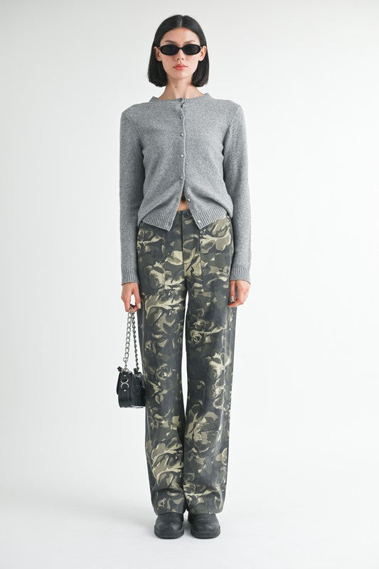 Person wearing a gray cardigan and camouflage pants on a white background