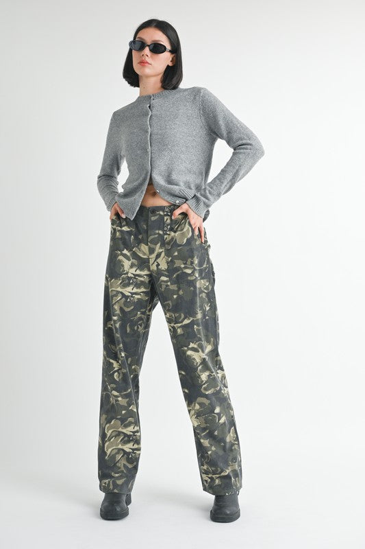 Person wearing a gray cardigan and camouflage pants on a white background