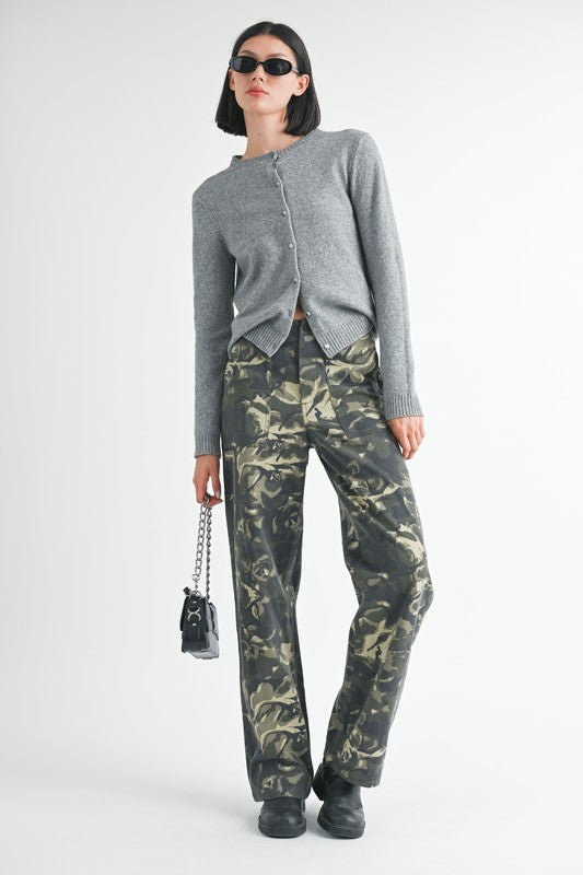 Woman wearing a gray cardigan and camouflage pants on a white background