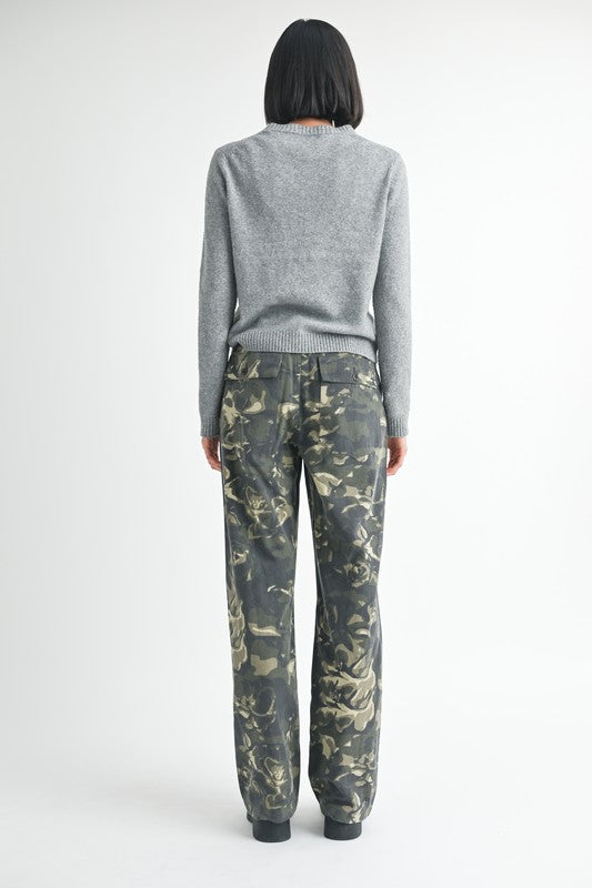 Person wearing a gray sweater and camouflage pants on a white background