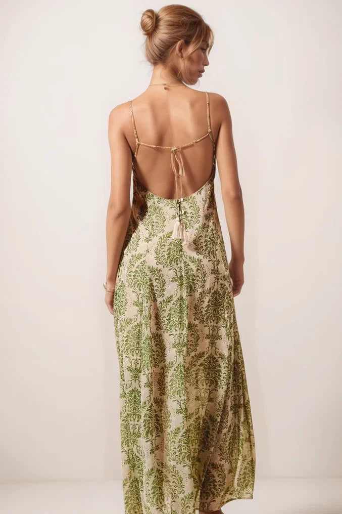 back view of the green damask maxi dress highlighting the dramatic open back, adjustable tie with tassels, and decorative white button detailing.