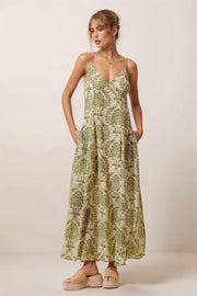 Side view of the green floral damask maxi dress showcasing the model with hands in the hidden side pockets.