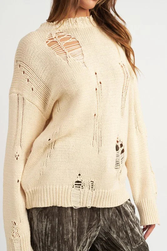 Cream sweater with distressed details worn by a person on a white background