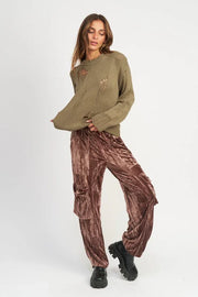 Woman wearing a green sweater and brown cargo pants on a white background