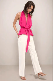 Woman wearing the hot pink elysian top and white jeans with her hands in her pockets in a walking motion