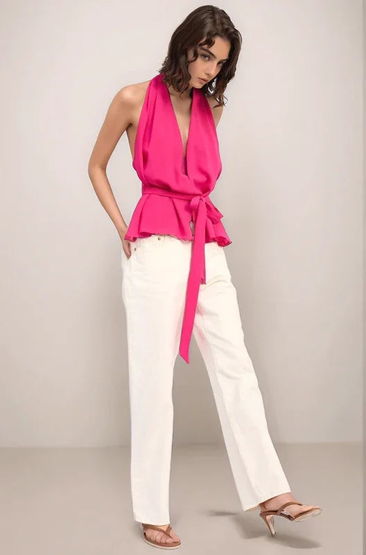 Woman wearing the hot pink elysian top and white jeans with her hands in her pockets in a walking motion