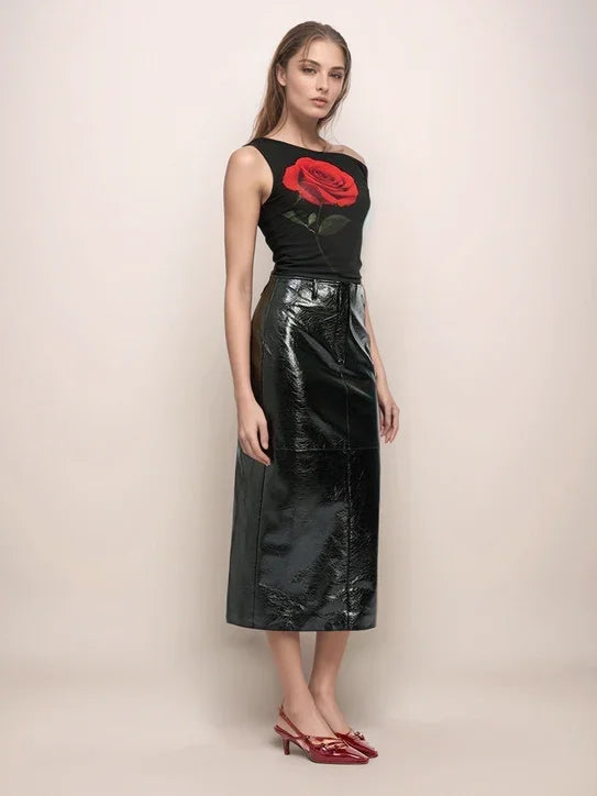 a woman wearing a black leather skirt and a black top with a large rose in front of a neutral background