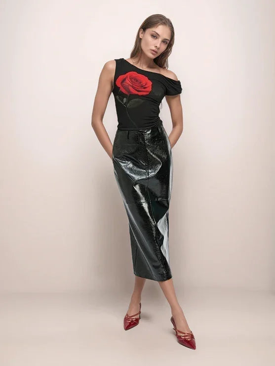 a woman wearing a black leather skirt and a black top with a large rose on it. 