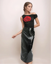 a woman wearing a black leather skirt and a black top with a large rose on it.