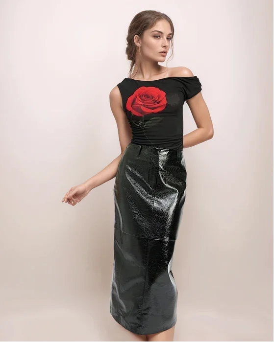 a woman wearing a black leather skirt and a black top with a large rose on it.