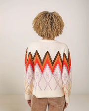 Person wearing a colorful patterned sweater with a neutral background