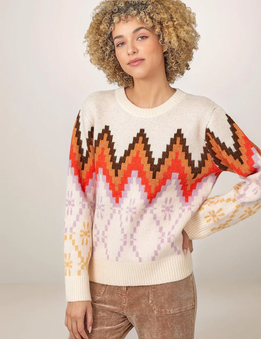 Woman wearing a colorful patterned sweater against a plain background