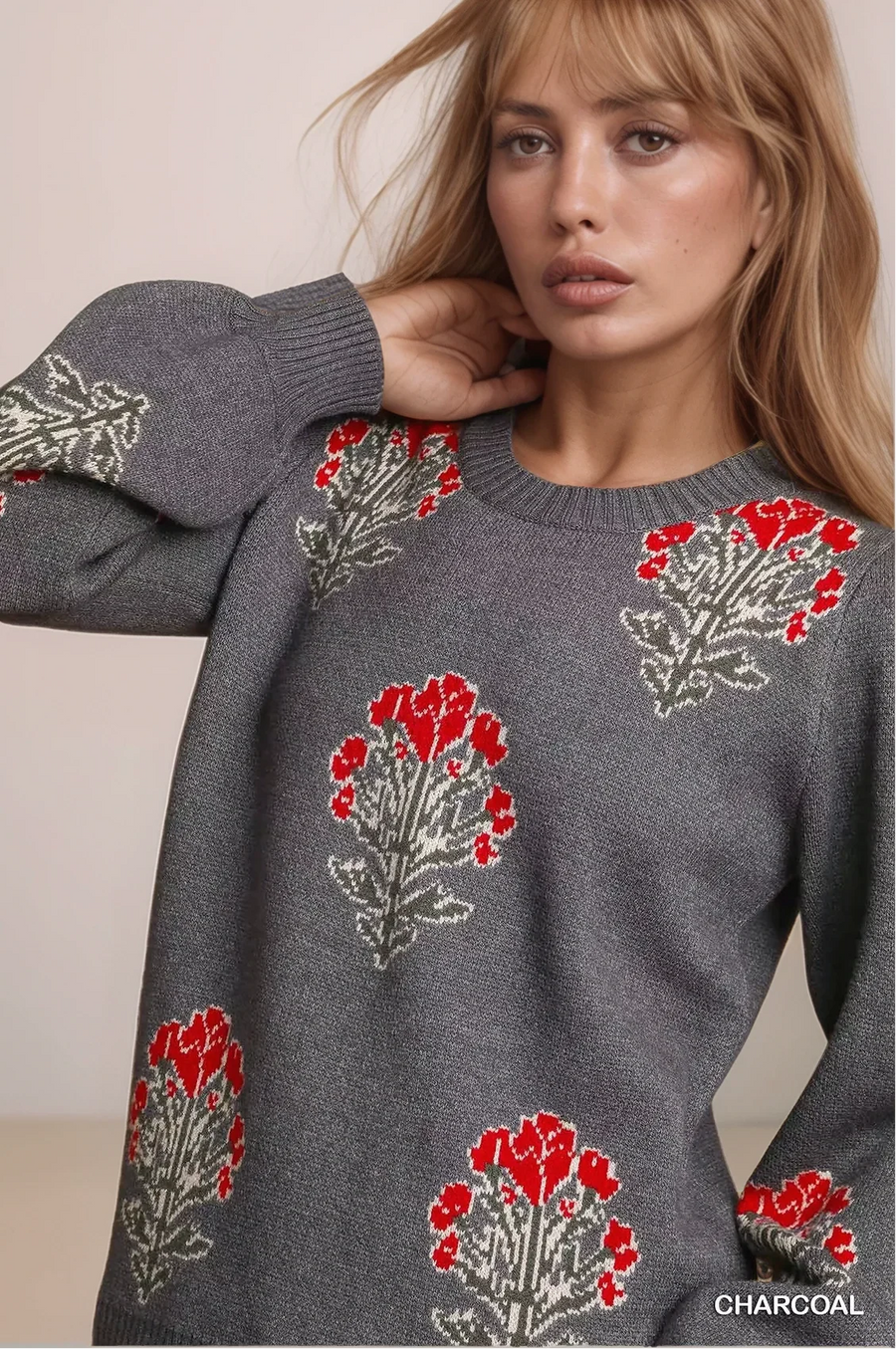 Woman wearing a charcoal gray sweater with floral patterns, brand 'CHARCOAL' visible.