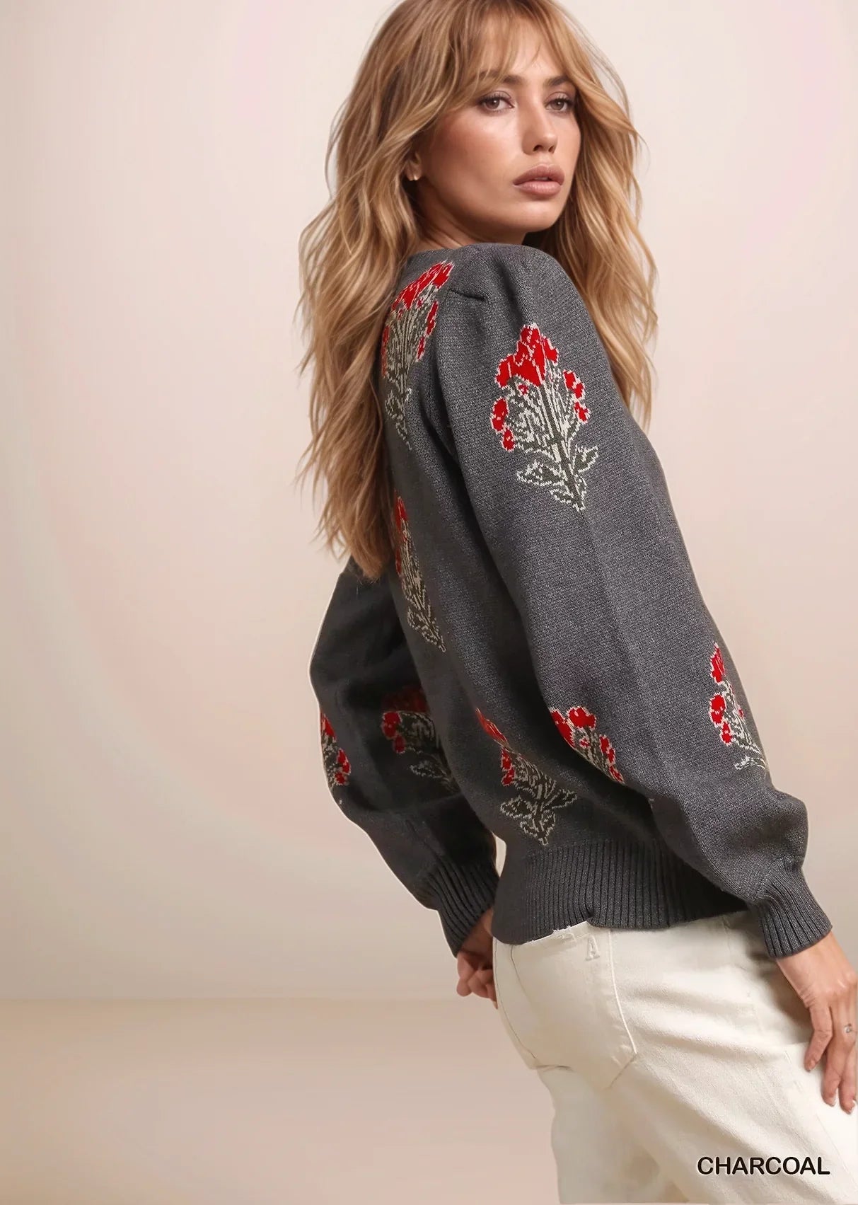 Woman wearing a charcoal gray sweater with floral embroidery on a beige background