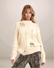 Woman wearing a distressed cream sweater against a plain background