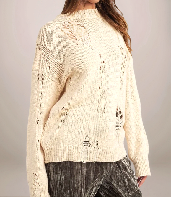 Beige sweater with distressed details worn by a person on a plain background