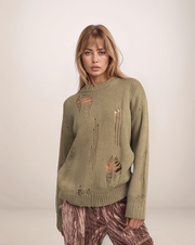 Woman wearing a green distressed sweater against a white background