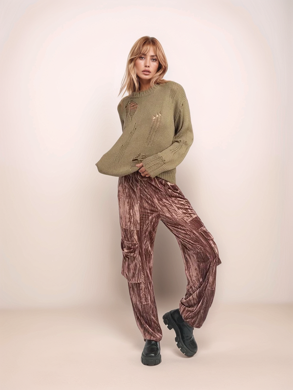 Woman wearing a green sweater and brown velvet pants on a white background