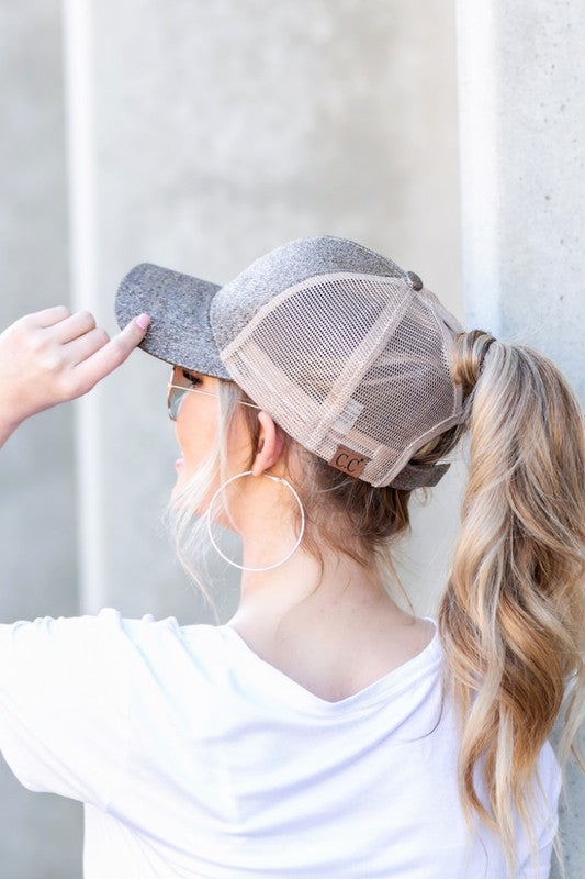 Person wearing a gray and beige mesh cap with a plain background