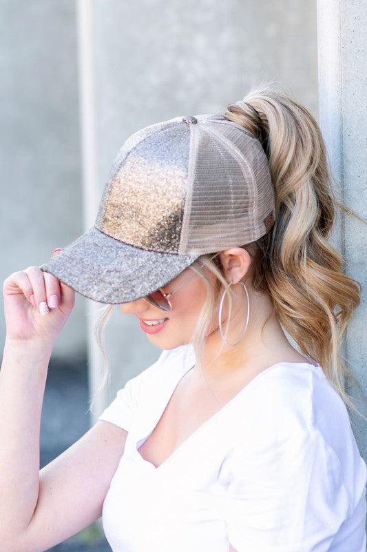 Woman wearing a glittery baseball cap against a neutral background