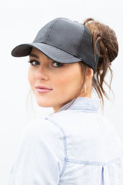 Woman wearing a gray baseball cap with a ponytail, on a white background