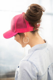 Person wearing a pink cap and hoop earring with a blurred background