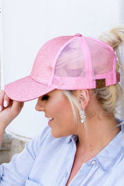 Woman wearing a pink glittery baseball cap with a blurred background