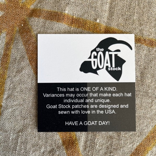 Label with 'the GOAT stock' logo and text on a textured fabric background