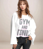 Woman wearing a white sweatshirt with 'GYM AND TONIC' text on a plain background