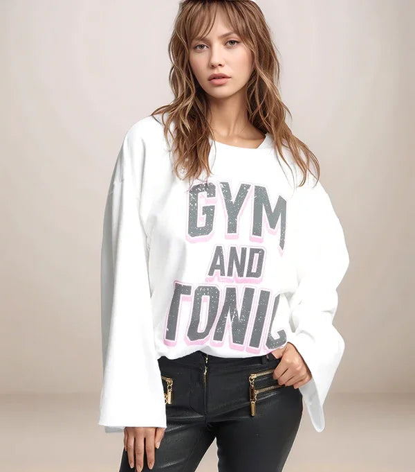 Woman wearing a white sweatshirt with 'GYM AND TONIC' text on a plain background