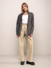 Person wearing a plaid shirt, white top, beige pants, and black shoes on a plain background