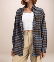 Person wearing a plaid shirt over a white crop top and beige pants on a beige background