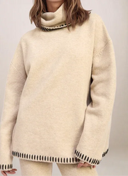 Beige sweater with black trim on a plain background