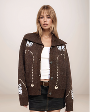 Woman wearing a brown patterned jacket on a plain background