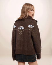 Woman wearing a brown jacket with cat face design on a beige background