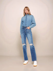 Woman wearing a denim outfit with a matching shirt and jeans on a beige background