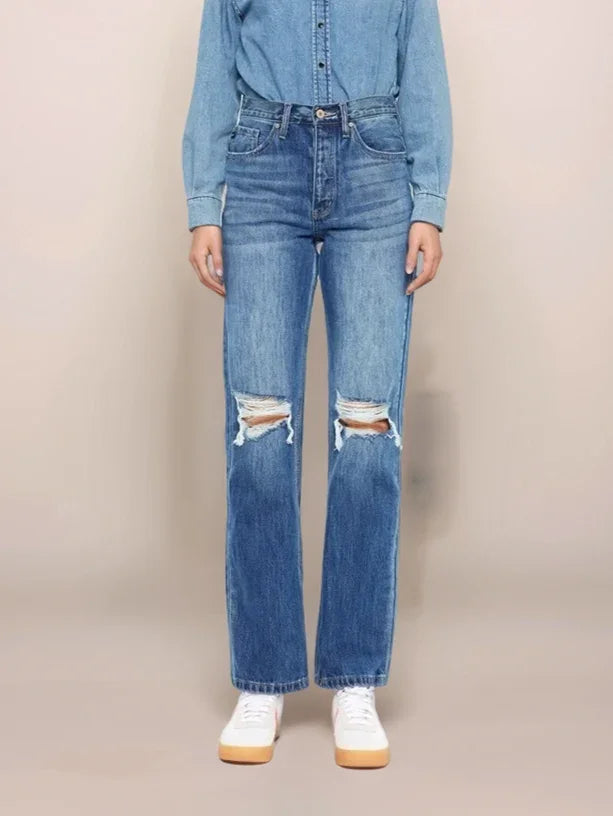 Person wearing a denim outfit with a matching denim shirt and jeans on a beige background