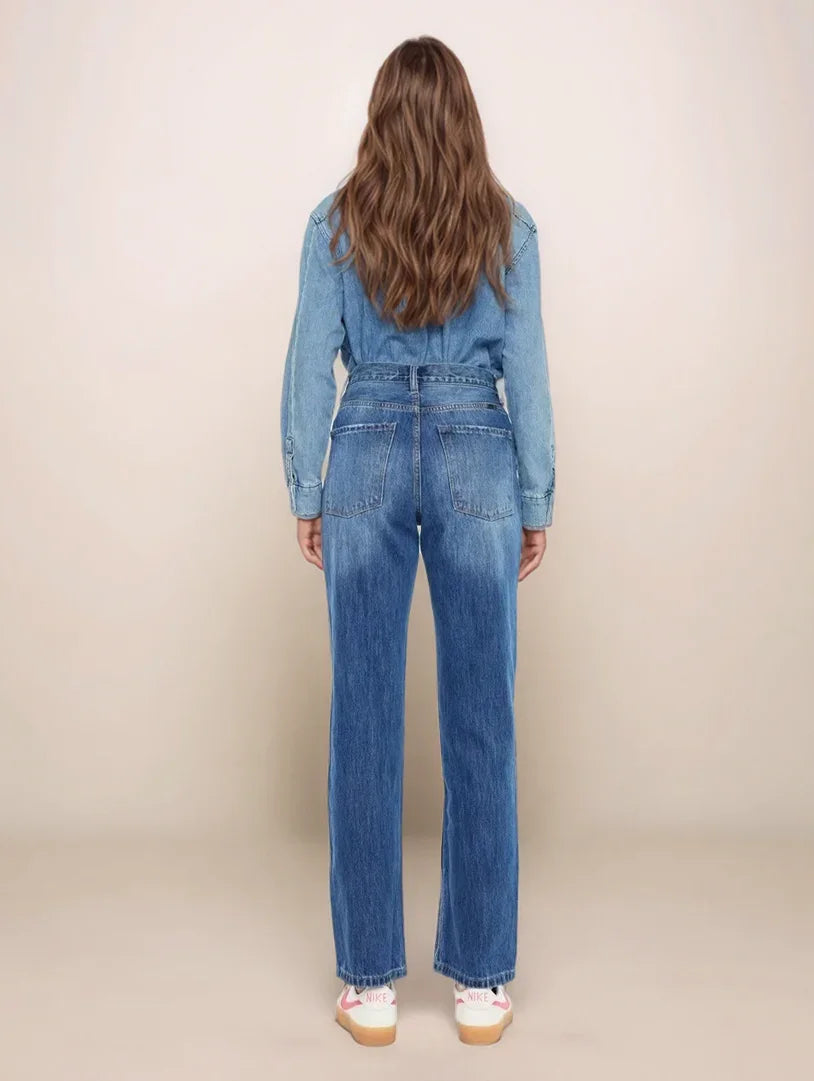 Person wearing a blue denim jumpsuit on a beige background