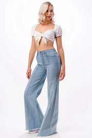 Woman wearing a white crop top and light blue jeans on a white background
