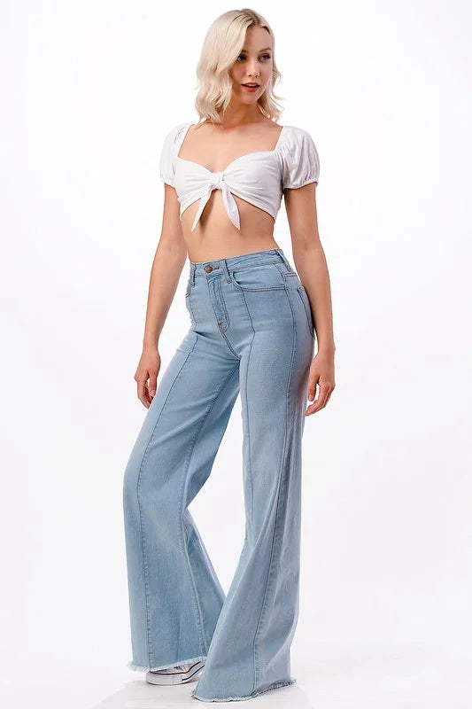 Woman wearing a white crop top and light blue jeans on a white background