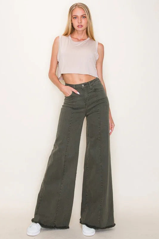 Woman wearing a beige sleeveless top and olive green wide-leg jeans against a white background