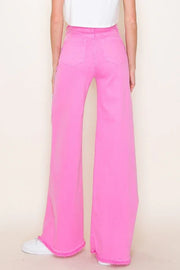 Person wearing bright pink wide-leg pants on a beige background