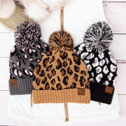 Three knitted hats with pom-poms on a white background