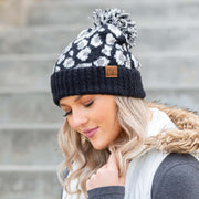Woman wearing a black and white patterned beanie with a pom-pom on a staircase.
